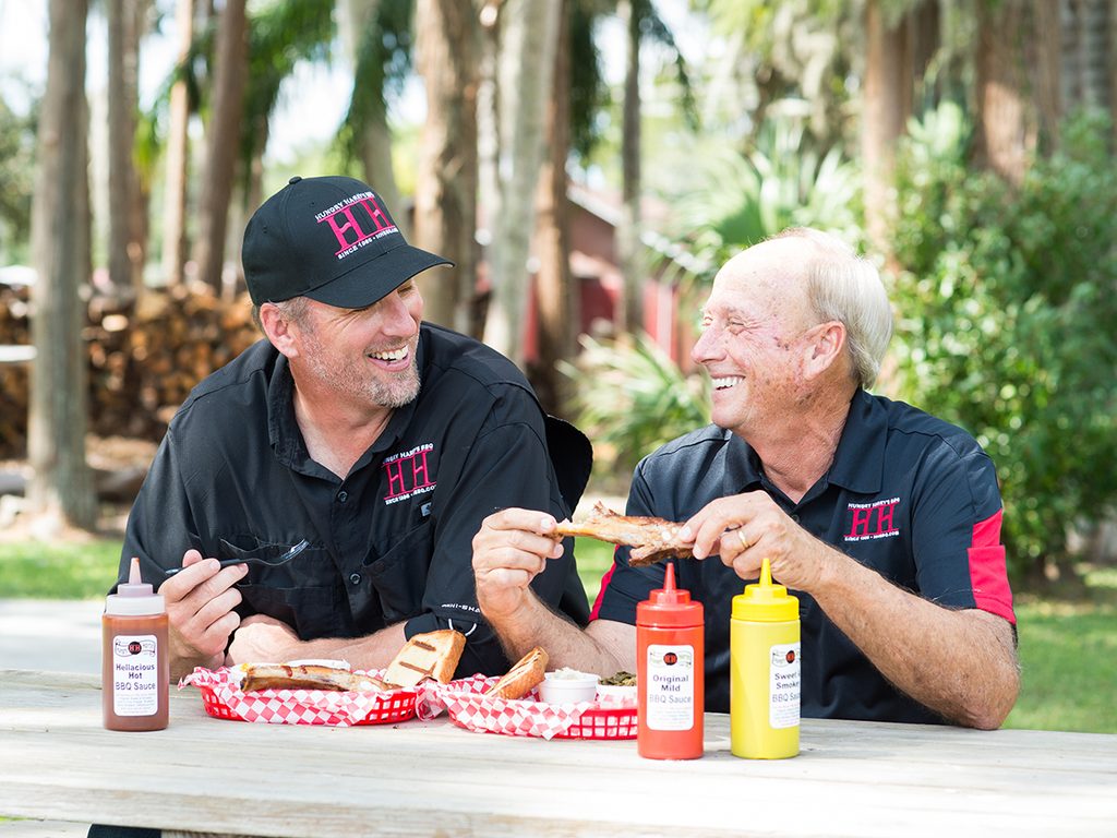 Two men enjoying barbecue together at an outdoor picnic table at Hungry Harry's, in Land O' Lakes, Florida