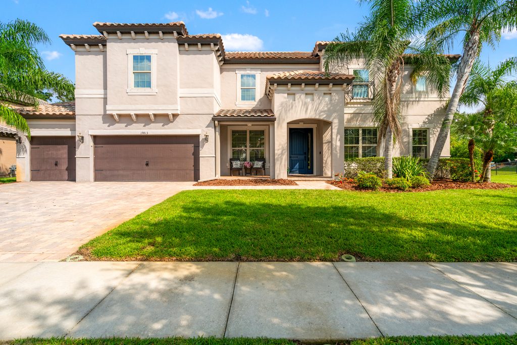 Two-story Florida home with palm trees, a three-car garage, and landscaped front yard